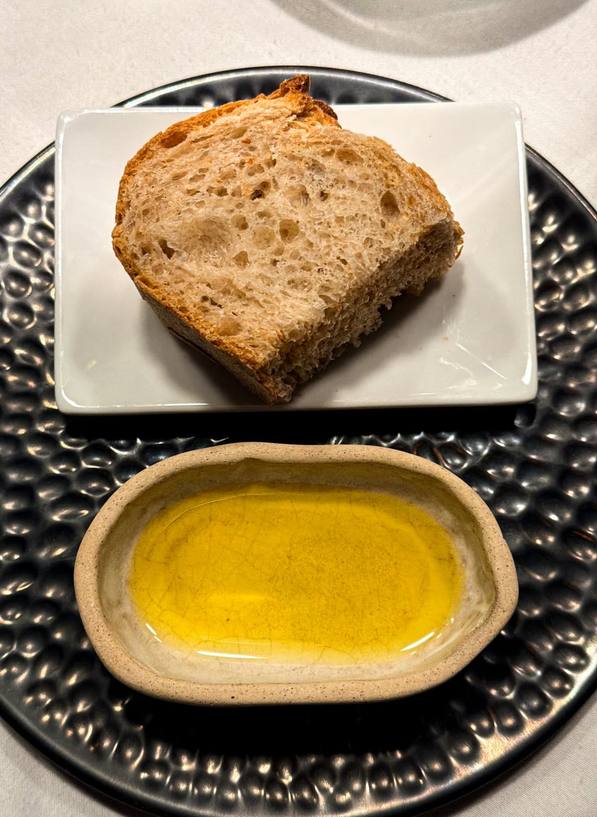 Pane croccante accanto a una ciotola di pietra con olio verde dorato